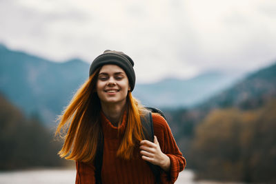 Portrait of beautiful woman standing against mountain