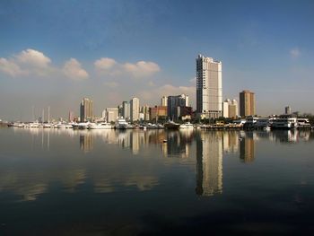 City at waterfront against cloudy sky