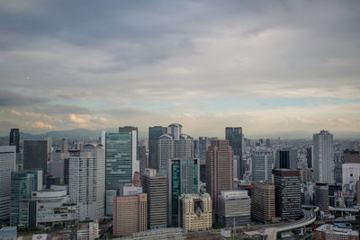 Skyscrapers in city against cloudy sky