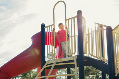Low angel view of child standing in slide at playground