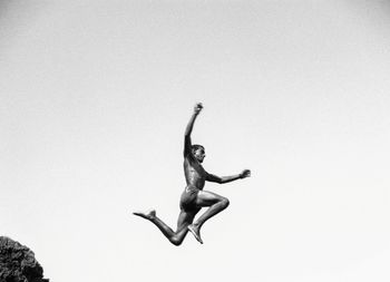 Low angle view of people jumping against clear sky