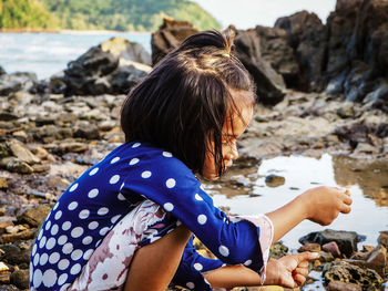 Rear view of girl on rock at beach