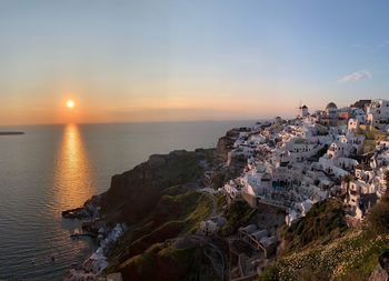 Aerial view of houses on mountain by sea against sky during sunset