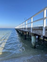 Bridge over sea against clear blue sky