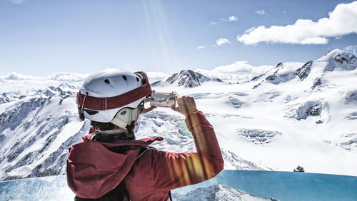 Rear view of man photographing through mobile phone against sky