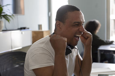 Cheerful businessman holding fist while sitting at office