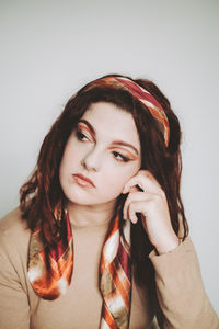 Portrait of young woman looking away against wall