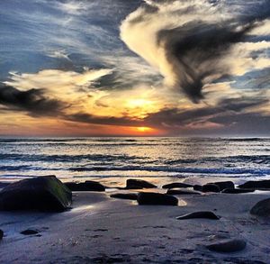 Scenic view of sea against cloudy sky during sunset