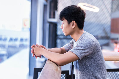 Side view of young man leaning on railing