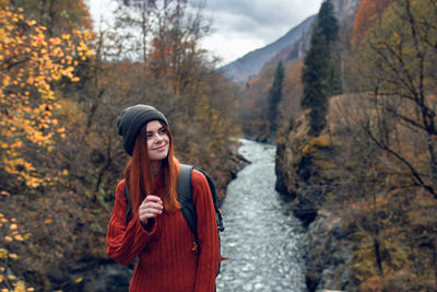 Smiling young woman standing in forest during autumn