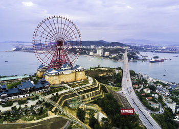 Ferris wheel by sea against sky