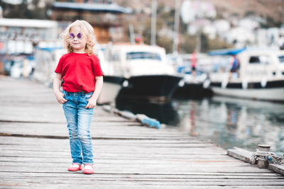 Smiling girl standing with hands in pockets on jetty