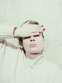 Close-up portrait of a woman against wall