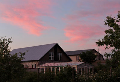 House by trees against sky at dusk