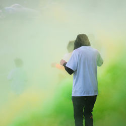 Rear view of mid adult man amidst green powder paint