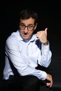 Young man sitting against black background