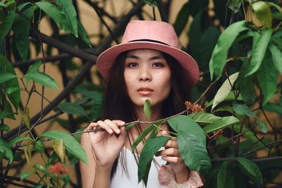 Portrait of young woman in hat amidst plants