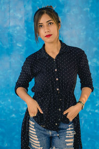 Portrait of beautiful woman standing against blue wall