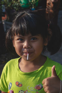 Close-up portrait of girl eating lollipop in darkroom at home