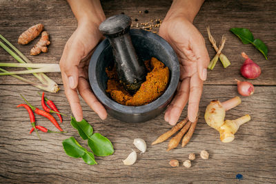 Cropped hands of person mixing spices on table