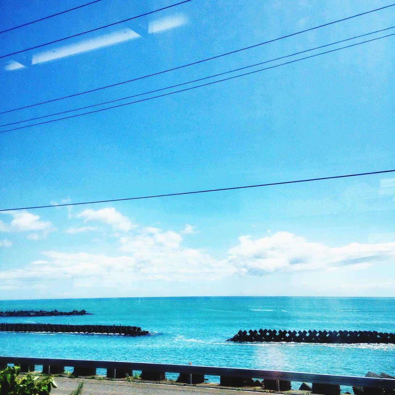 sea, horizon over water, water, blue, sky, tranquility, tranquil scene, scenics, beauty in nature, nature, railing, transportation, beach, connection, outdoors, day, cable, no people, idyllic, sunlight