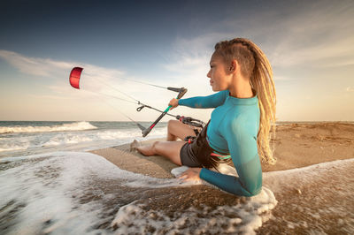 Woman sitting on beach during kite surfing