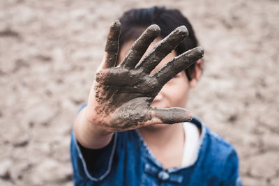 Close-up of girl with muddy hand on drought field