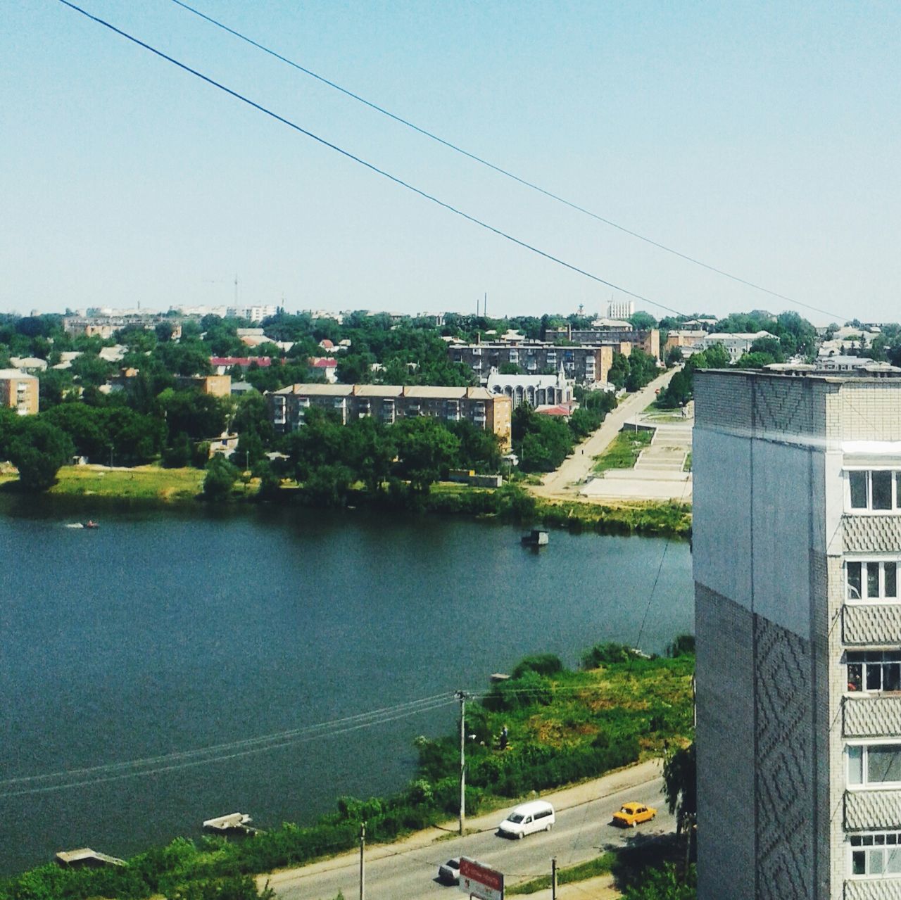 building exterior, architecture, built structure, clear sky, city, cityscape, water, residential structure, residential building, river, transportation, high angle view, residential district, copy space, tree, road, connection, house, day, car