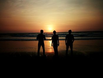 Silhouette people on beach against sky during sunset