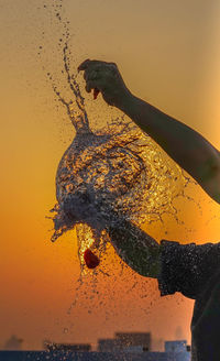 Close-up of silhouette man splashing water at sunset