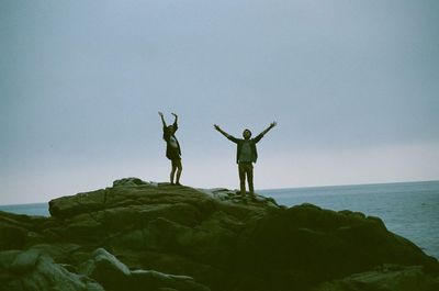 Friends standing on sea shore against clear sky