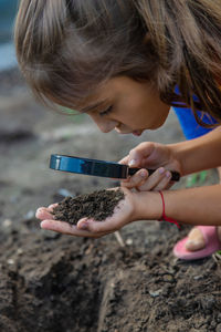 Girl looking at soil through magnifying glass