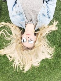 Directly above shot of woman with blond hair lying down on field