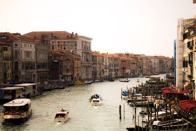 Boats on canal amidst buildings in city