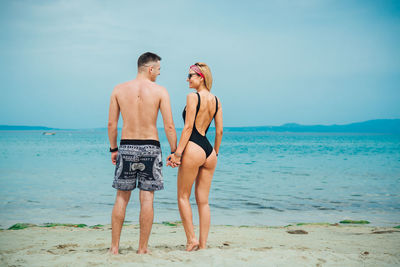 Young couple spending leisure time at beach against sky