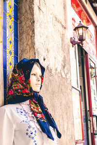 Woman looking away while standing against window