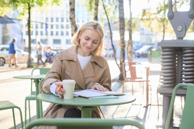 Portrait of young woman using mobile phone while sitting in cafe