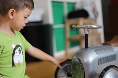 Boy playing with toy car on hardwood floor at home