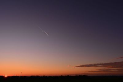 Low angle view of silhouette vapor trail against sky during sunset