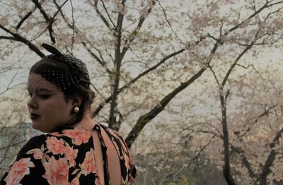 Portrait of woman looking away against trees