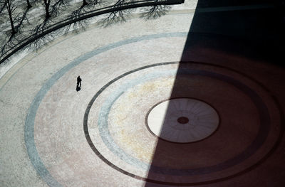 High angle view of silhouette person walking on footpath during sunny day