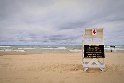 Text on empty lifeguard chair at sandy beach