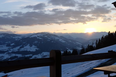 Scenic view of snow covered mountains against cloudy sky