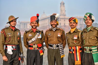 Portrait of friends standing in traditional clothing against sky