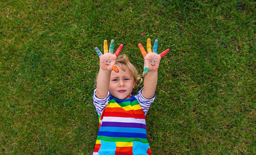 Portrait of boy playing with arms raised standing on grassy field
