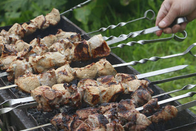 Hand holding meat on barbecue grill