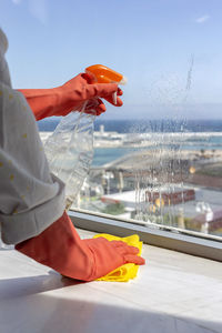 Cropped hand of man cleaning window