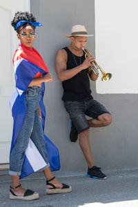 Full length of young couple holding hands against wall