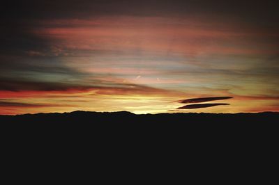 Silhouette landscape against dramatic sky during sunset