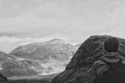 Rear view of man standing on mountain against sky